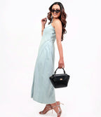 Woman in a light blue dress holding a black handbag on a white background