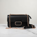 Karryol Mona black crossbody bag with gold chain strap and buckle detail. Structured design with top zip closure.