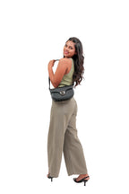 Karryol Bella black leather crossbody bag with gold-tone hardware and adjustable strap, worn by a woman.