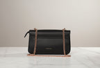 Karryol Mona black leather crossbody bag with gold chain strap and zip closure.
