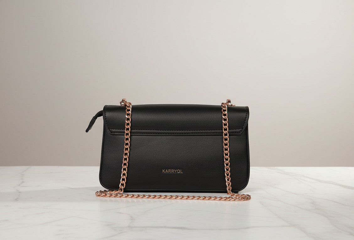 Karryol Mona black leather crossbody bag with gold chain strap and zip closure.
