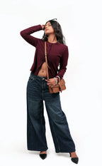 KARRYOL tan leather Kari crossbody bag with embossed monogram panel and gold-tone hardware, worn by a model with dark hair and jeans.