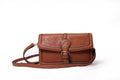 KARRYOL tan leather crossbody bag with embossed monogram panel and gold-tone buckle closure.
